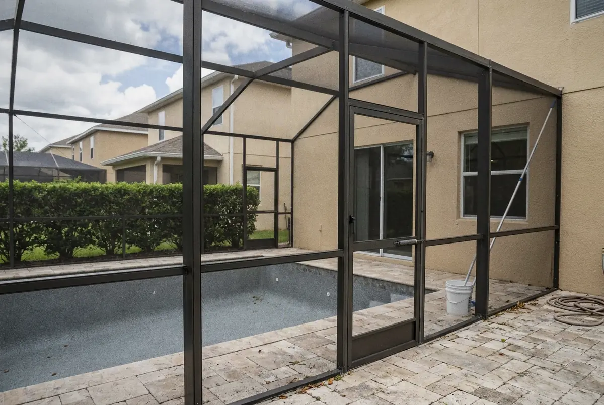 Screened pool with a travertine-look paver deck behind a newer two-story stucco home, Lake Mary, FL